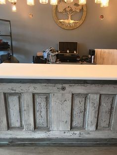 a white counter top sitting in front of a wall mounted light fixture with lights on it