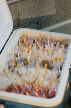 several toothpicks are in a plastic container on the table next to some food