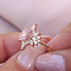 a close up of a person's hand holding a ring with diamonds on it