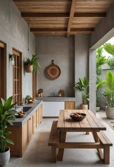 an outdoor kitchen with wooden benches and potted plants on the counter top, along with a sink