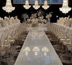 a long table with chairs and chandeliers is set up for a formal function