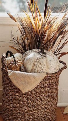 a basket filled with lots of different types of pumpkins and grass in it's center