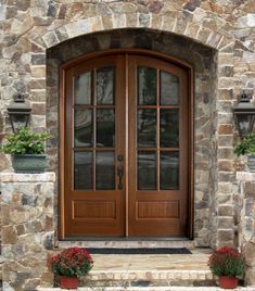 a stone house with two double doors and flower pots