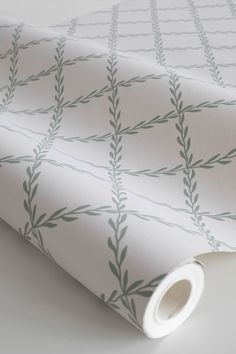 a white wallpaper with black leaves and vines printed on it's side, next to a roll of tape