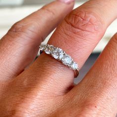 a woman's hand with a three stone ring on her left and an engagement band on the right