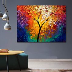 an abstract painting of a colorful tree on a gray wall above a green chair and table