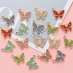 the colorful butterfly charms are on display in front of a pink background and white frame