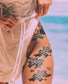 a woman's legs with tattoos on them and water in the backgroud