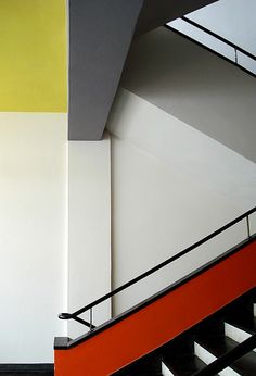 an orange and white stair case next to a black hand rail