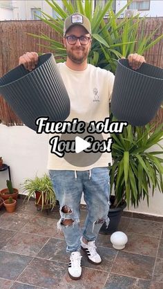 the man is holding up two large fan like objects in his hands and smiling at the camera