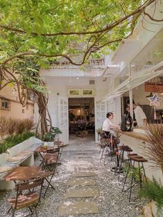 people are sitting at tables in an outdoor cafe with lots of greenery on the roof