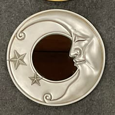 a metal moon and star decoration on a gray surface next to a gold plated object