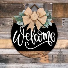 a welcome sign hanging on the side of a wooden wall with a bow around it