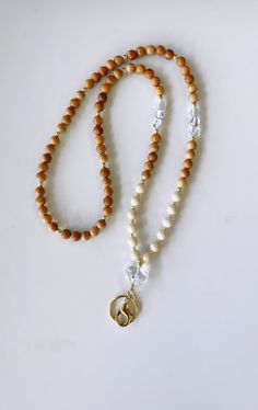 a beaded necklace with a gold charm and white beads on a white table top