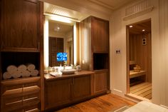 a large bathroom with wooden cabinets and white towels on the counter top, in front of a television