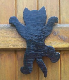 a wooden door handle with a black cat on it's back and arms stretched out to the side