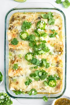 an enchilada casserole in a glass dish with cilantro, jalapenos and cheese