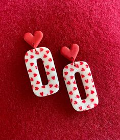 two red and white heart shaped earrings on a red carpet with the word love written in it