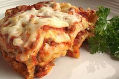 a white plate topped with lasagna and parsley