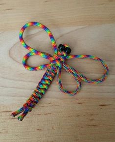 a multicolored tie - dye dragon knot on a wooden table with black bells