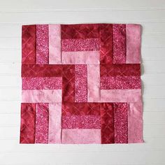 a piece of pink and red quilted material on a white wall with wood flooring