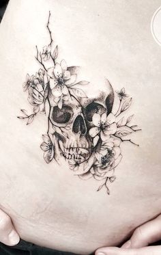 a woman's stomach with a skull and flowers on it