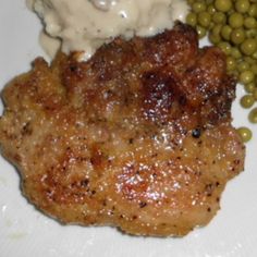 a white plate topped with meat, peas and mashed potatoes