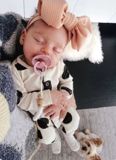 a baby with a pacifier in its mouth laying on the floor next to a dog