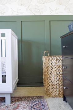 a baby crib next to a dresser with a blanket on it and a rug in front of it