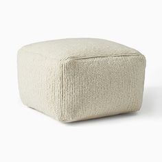 a white square ottoman sitting on top of a floor