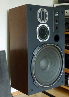 a large speaker sitting on top of a wooden shelf