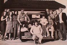 an old black and white photo of people posing in front of a car