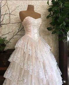 a white wedding dress on display in front of a plant