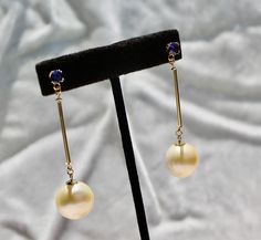 "These are 100% 14k solid gold, starting with the beautiful and ornate tanzanite posts(5mm round), to the 1\" tubes leading to the pearl caps. The HUGE ocean off-white pearls from the South Seas are almost round and measure 16x15x14mm, are very smooth and have a beautiful luster (AAA). They fit perfectly into the style of Art Deco jewelry, giving the design a pendulum style. The quality of the tanzanite is excellent at VS1. Length is 2.25\" from top to bottom. TANZANITES was first discovered in Elegant Tanzanite Round Earrings, Elegant Round Tanzanite Earrings, Elegant Tanzanite Earrings, Elegant Gold Tanzanite Earrings, Formal Gold Tanzanite Earrings, Solid Gold Earrings, South Seas, Deco Jewelry, Art Deco Jewelry