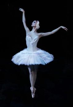 the ballerina is dressed in white tutu and holding her arms out to the side