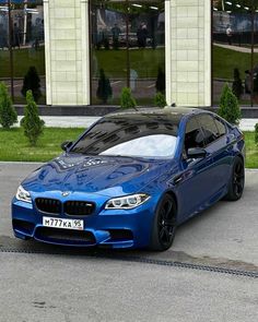 a blue bmw is parked in front of a building on the side of the road