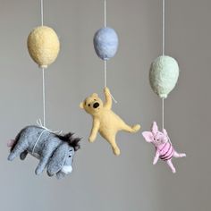 three stuffed animals hanging from strings with balls in the shape of an animal and pig