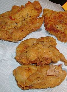 four fried chicken pieces are sitting on a paper towel