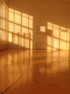 an empty basketball court with the sun shining through the windows