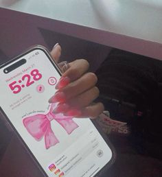 a woman's hand holding an iphone with pink bows on it