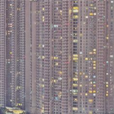 an aerial view of many tall buildings at night time, with lights on the windows