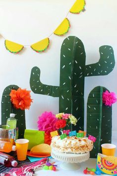 a birthday party with a cake, cactus and other decorations on the table in front of it