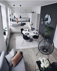 a living room filled with furniture and a white table surrounded by black chairs on top of a hard wood floor