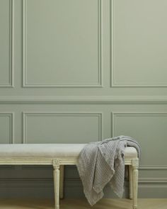 a white bench with a blanket on it in front of a green paneled wall