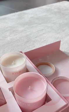 a pink box with two candles and some other items in it