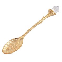 a gold spoon with a crystal in the middle