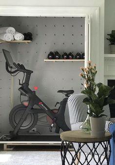 there is a bike in the living room next to a table with flowers on it