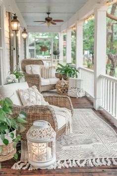 a porch with wicker furniture and plants on the front porch, along with lanterns