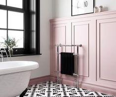 a bathroom with pink walls, black and white flooring and a claw foot bathtub