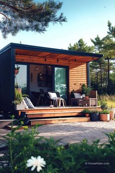 a small house with steps leading to the front door and patio area, surrounded by greenery